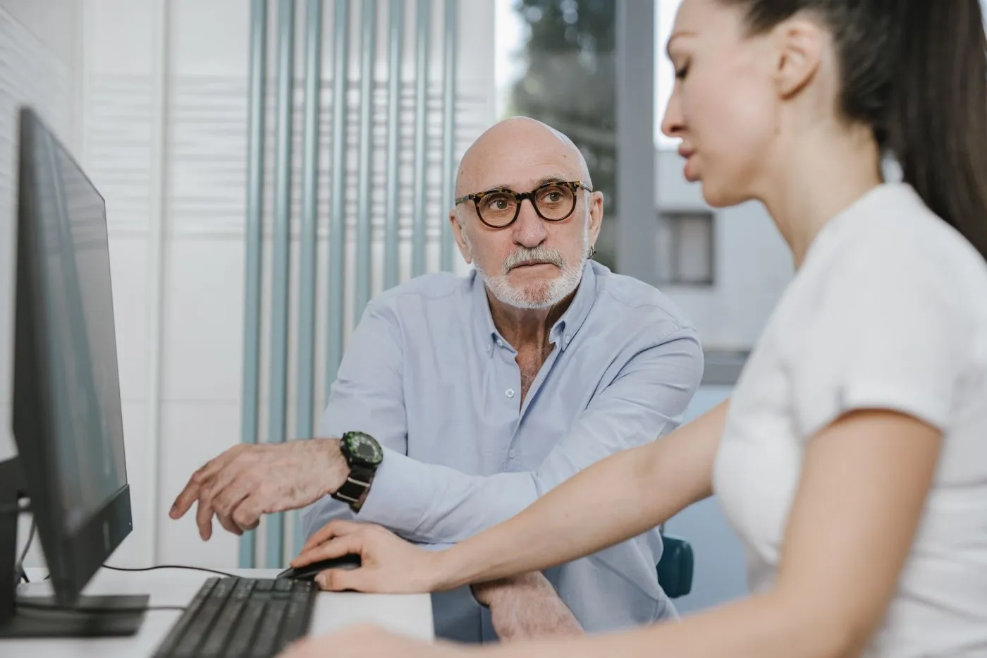 A clinician walking an older patient through information on a screen