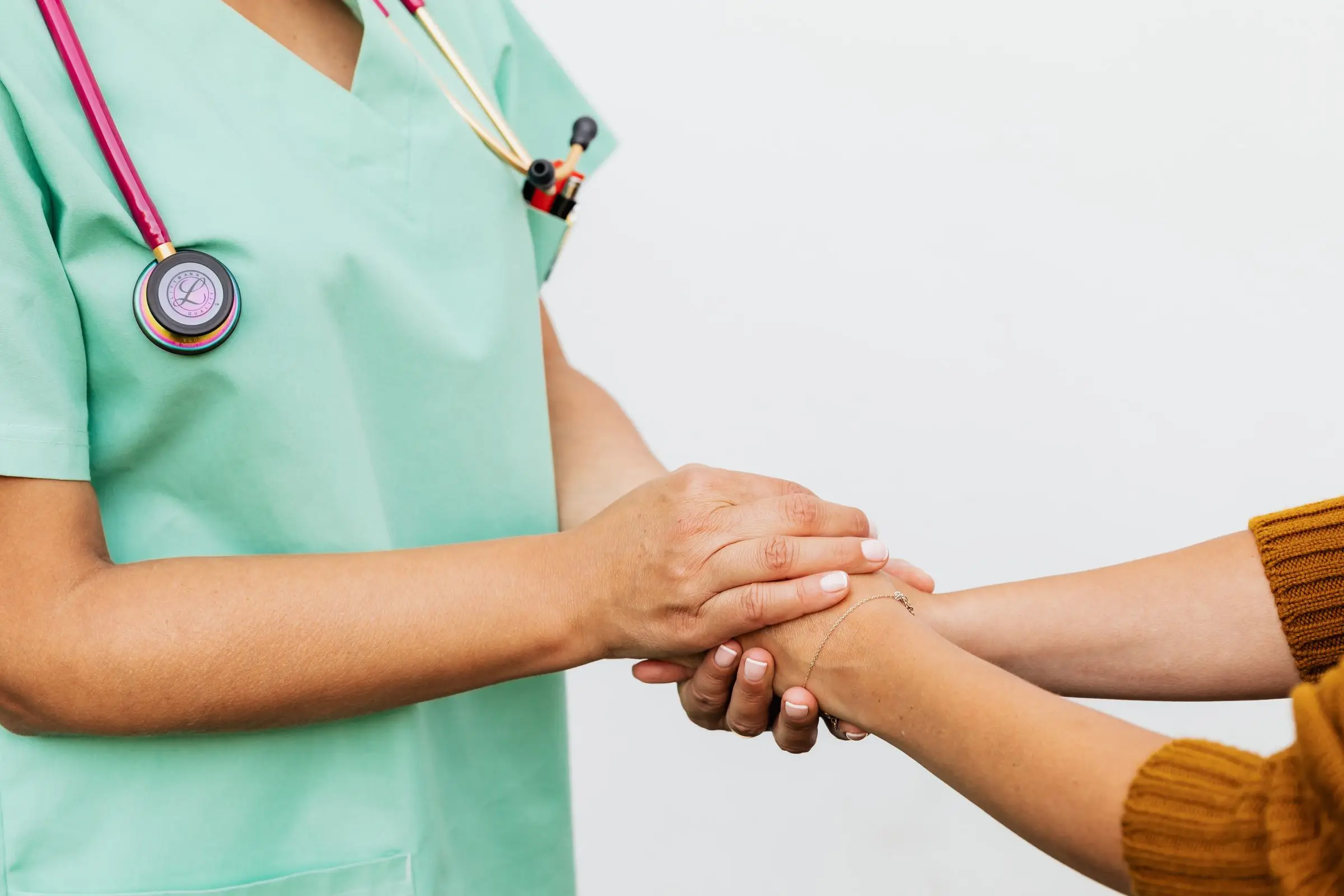 A clinician warmly holding a patient’s hands