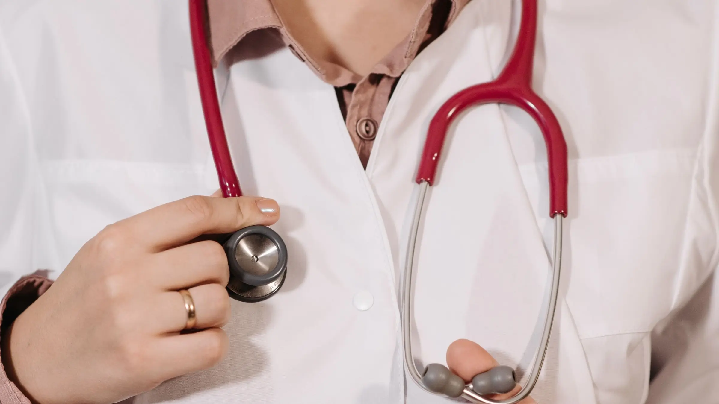 A physician in a white coat holding a stethoscope