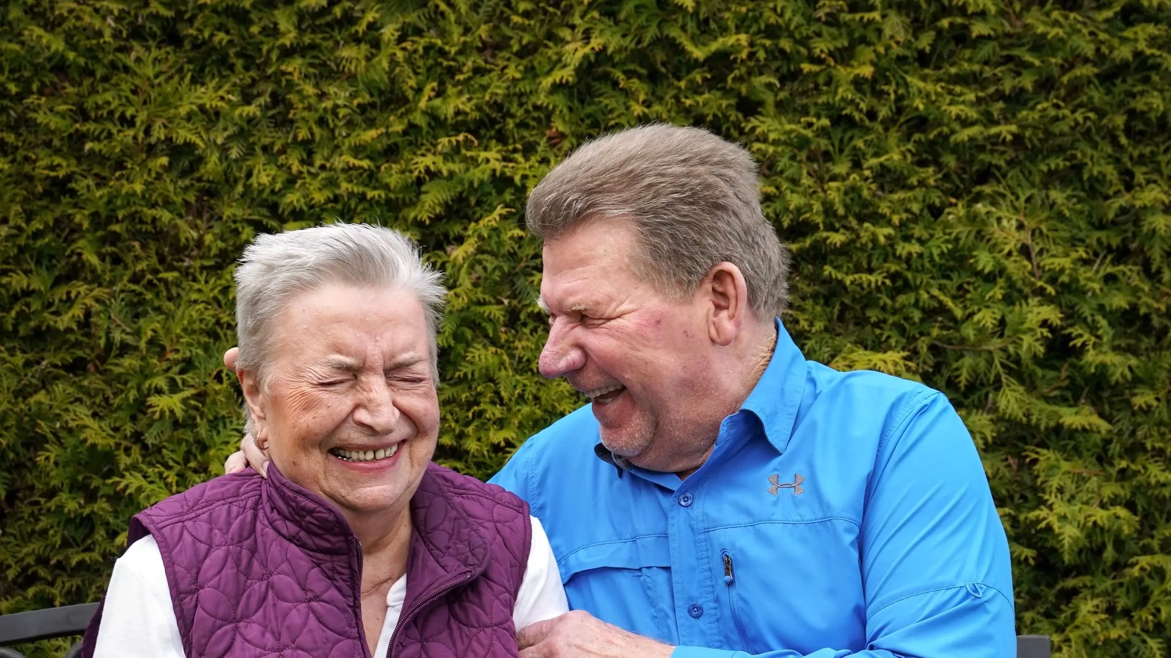 An older couple laughing together on a park bench